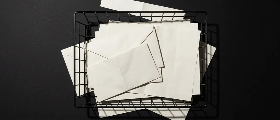 An inbox tray of envelopes and letters on a black background